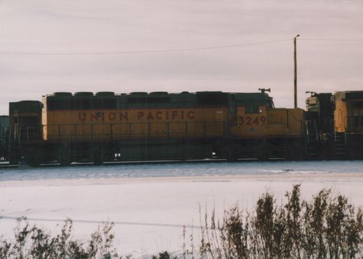 Side view of a Union Pacific diesel locomotive numbered 3249 in a snow-covered yard, with another locomotive behind it.