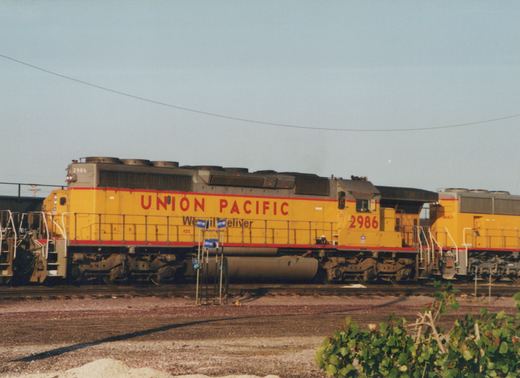 Two yellow Union Pacific diesel locomotives, 2986 and 4662, are coupled together in a gravel rail yard under a clear sky.