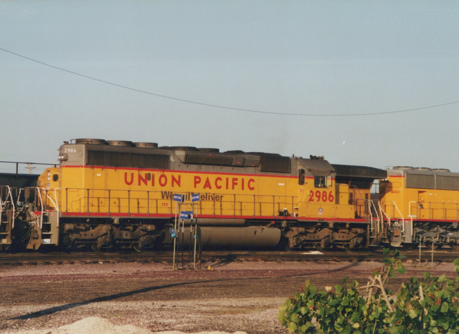 Two yellow Union Pacific diesel locomotives, 2986 and 4662, are coupled together in a gravel rail yard under a clear sky.