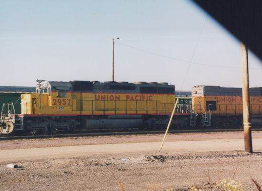 Side view of a Union Pacific SD40 diesel locomotive numbered 2957, parked in a rail yard with another UP locomotive and a freight car nearby.