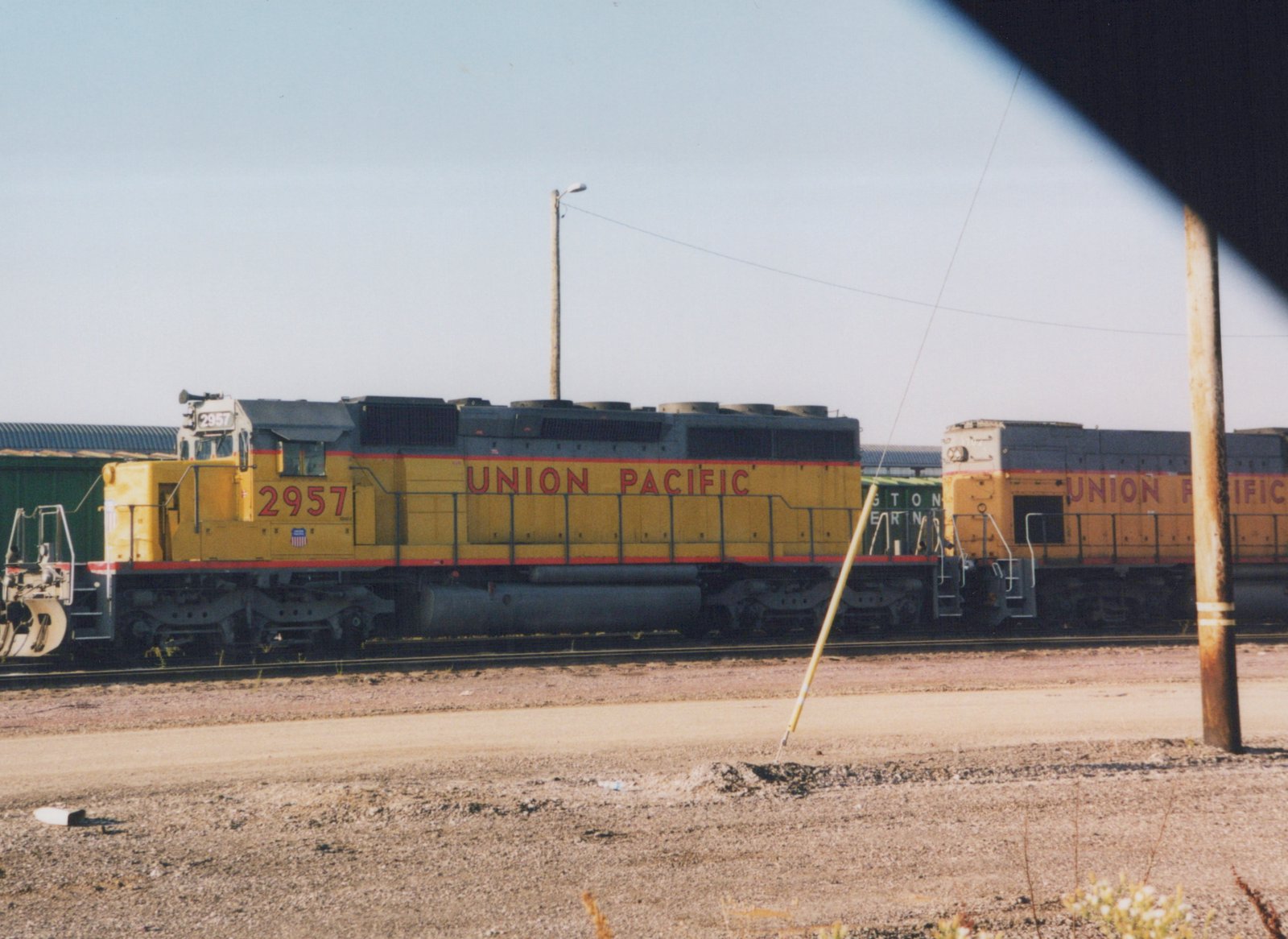 Side view of a Union Pacific SD40 diesel locomotive numbered 2957, parked in a rail yard with another UP locomotive and a freight car nearby.