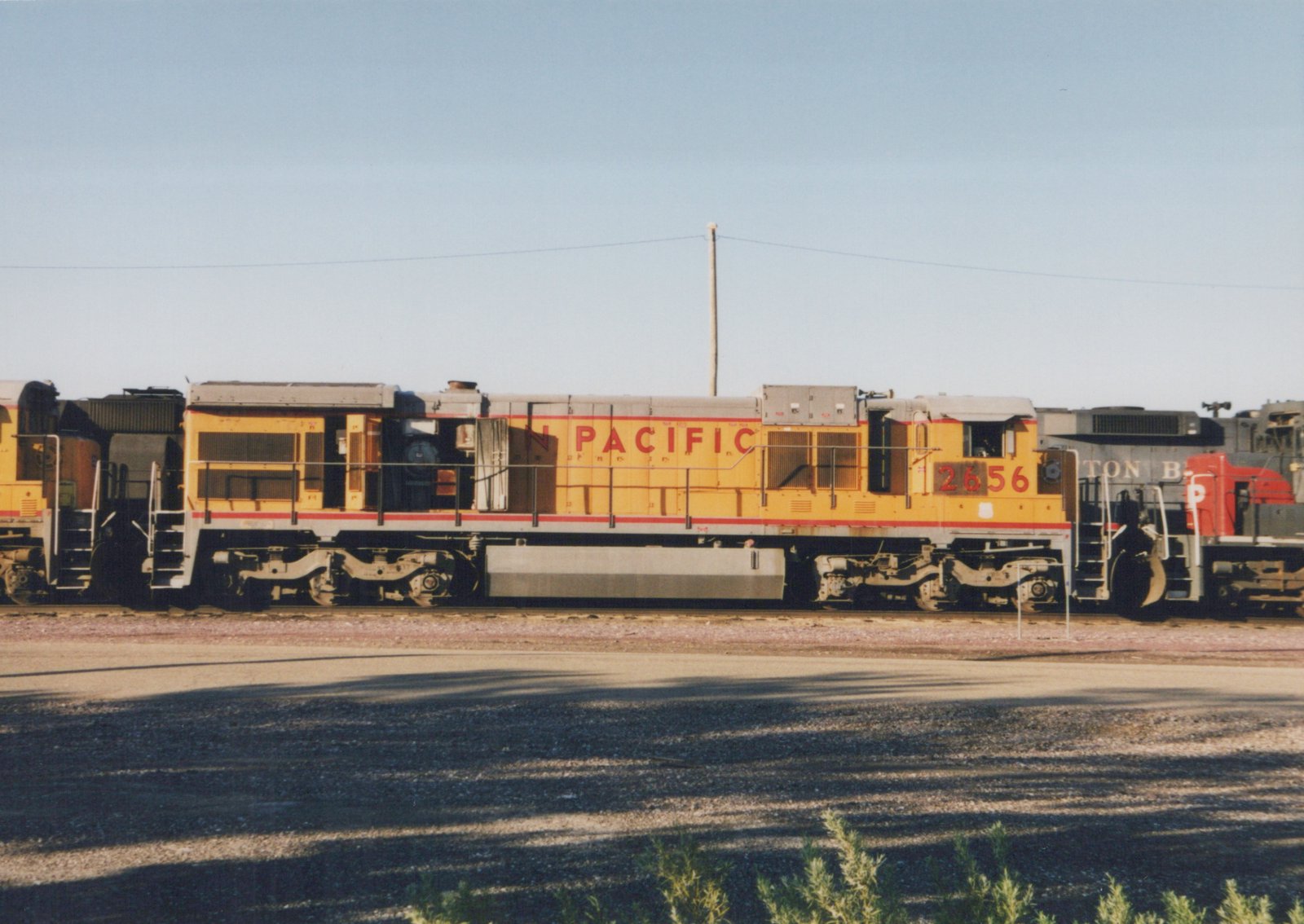 A yellow and gray Union Pacific diesel locomotive, number 2656, is parked in a rail yard with another locomotive partially visible behind it.