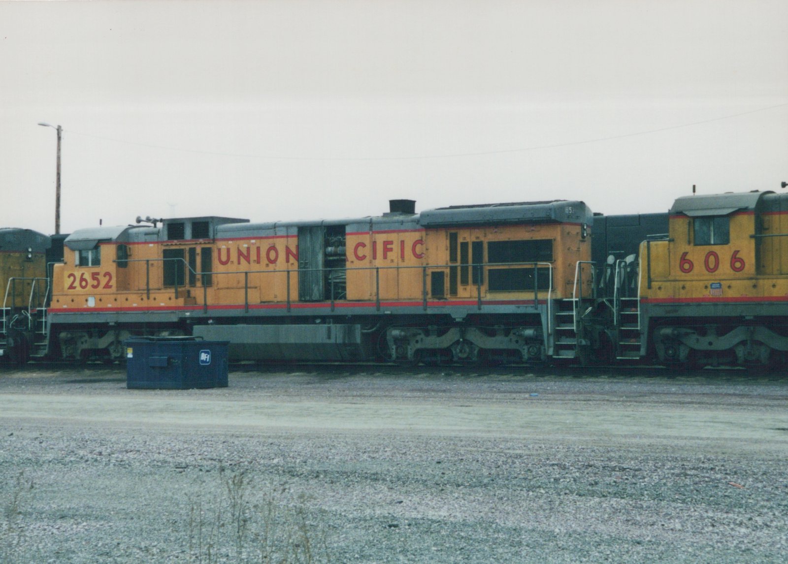Two yellow and gray Union Pacific diesel locomotives with red stripes sit on tracks in a gravel yard, with locomotive 2652 in the foreground and 606 behind it.