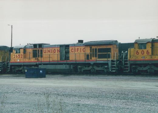 Two yellow and gray Union Pacific diesel locomotives with red stripes sit on tracks in a gravel yard, with locomotive 2652 in the foreground and 606 behind it.