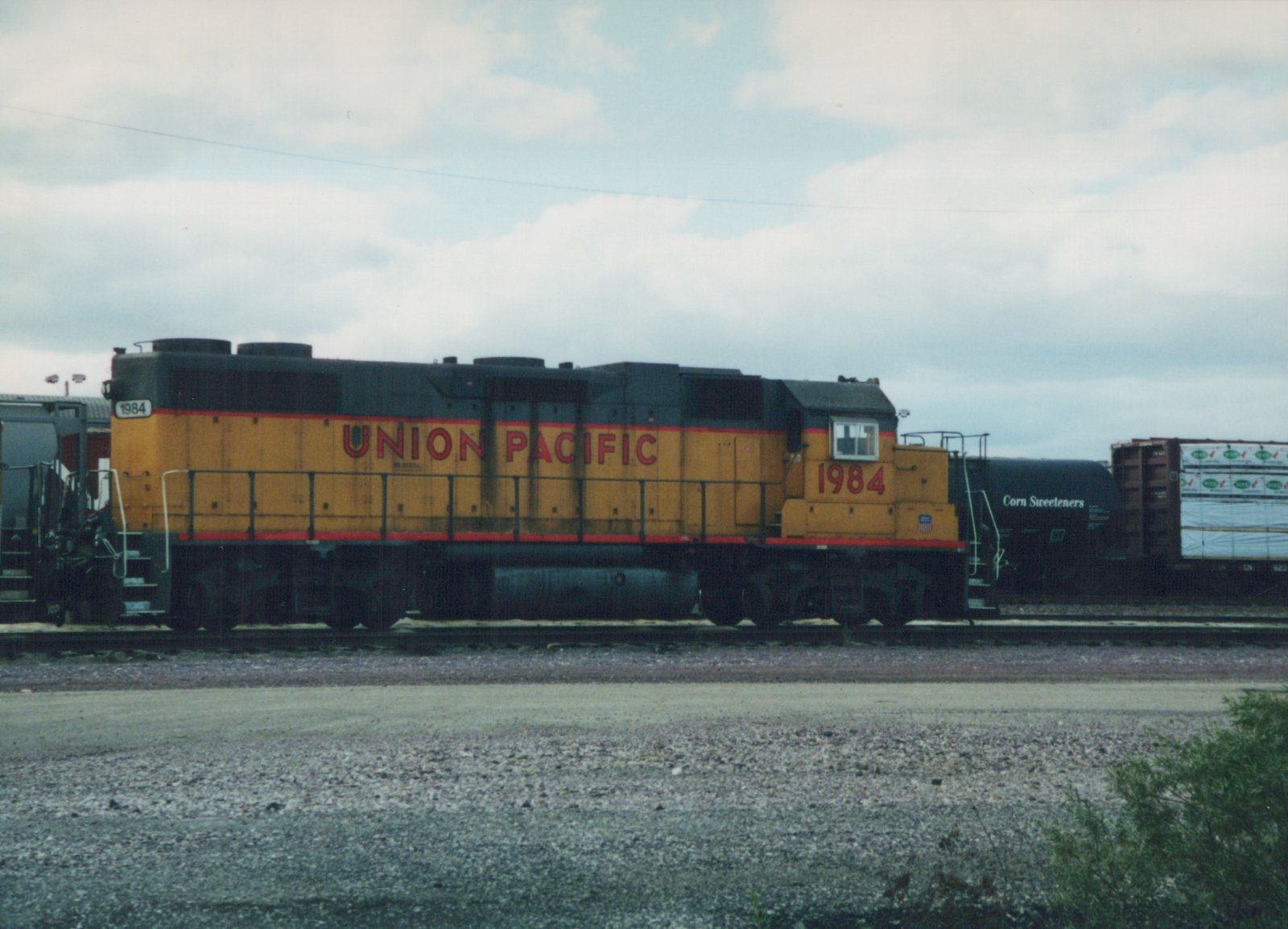 Side view of a Union Pacific diesel locomotive with the number 1984, pulling freight cars on a cloudy day at a rail yard.