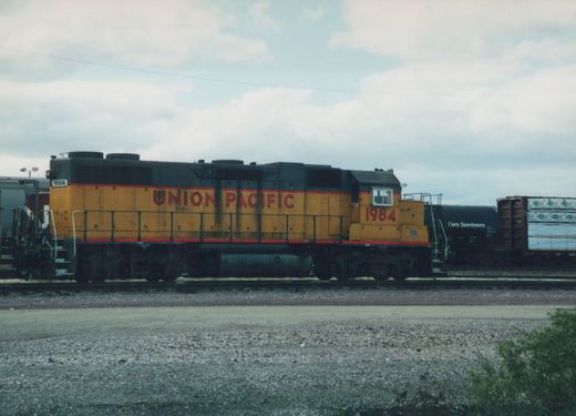 Side view of a Union Pacific diesel locomotive with the number 1984, pulling freight cars on a cloudy day at a rail yard.