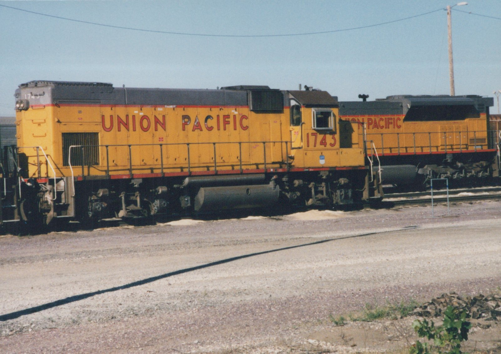 Two yellow Union Pacific diesel locomotives, including number 1743, parked in a gravel yard on a sunny day.