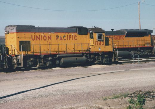 Two yellow Union Pacific diesel locomotives, including number 1743, parked in a gravel yard on a sunny day.