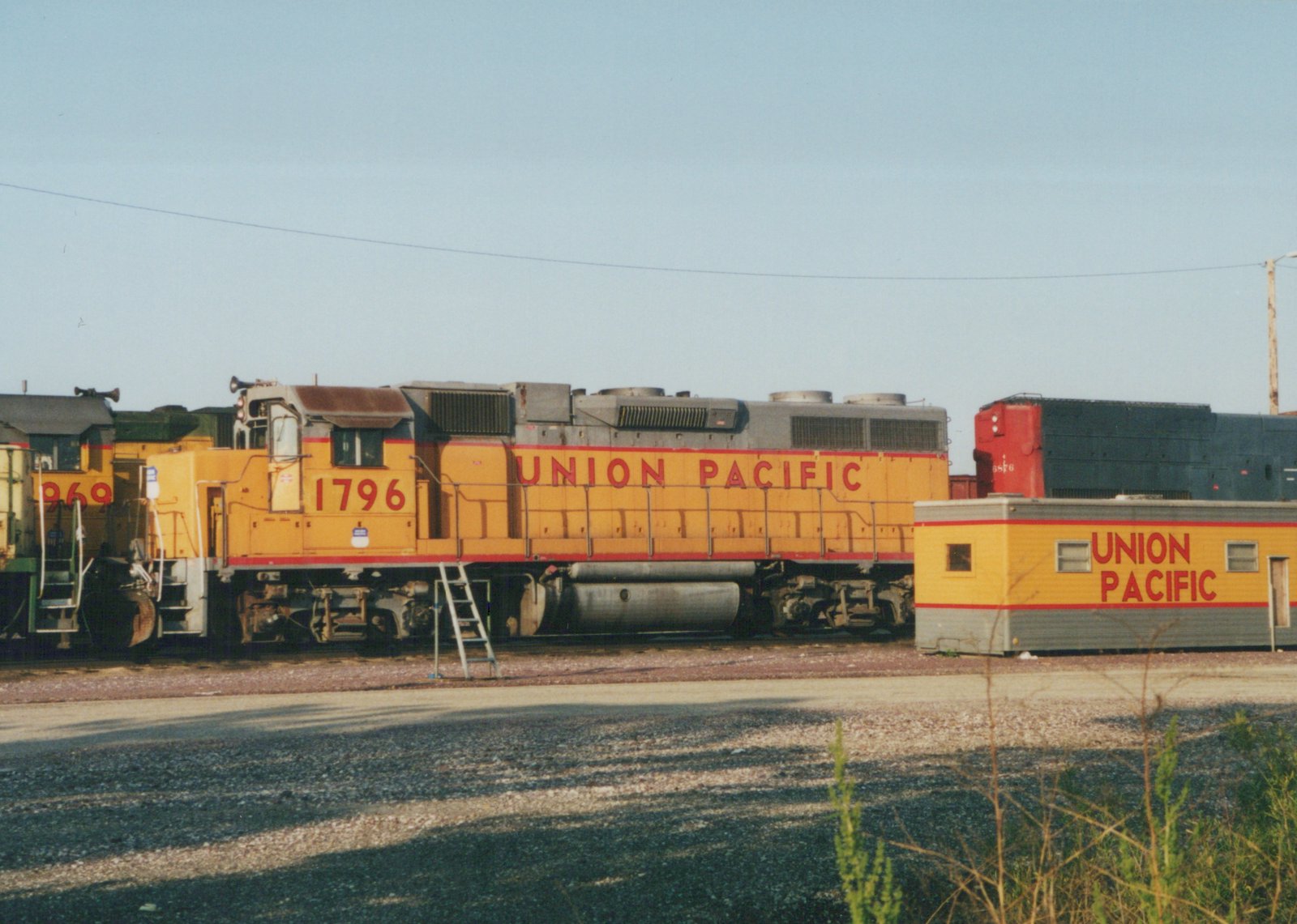 A yellow Union Pacific EMD SD40-2 locomotive numbered 1796 is parked in a yard with other locomotives in the background.