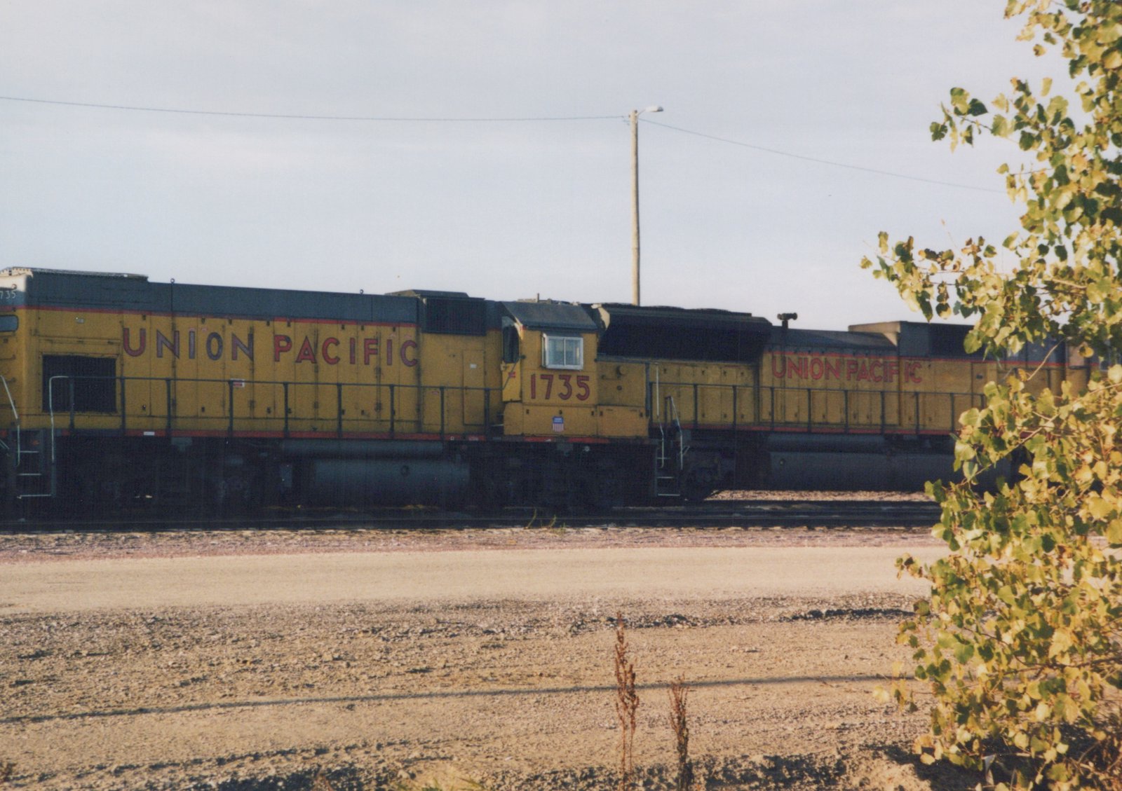 Side view of two yellow Union Pacific diesel locomotives on a railroad track, with the lead unit numbered 1735.