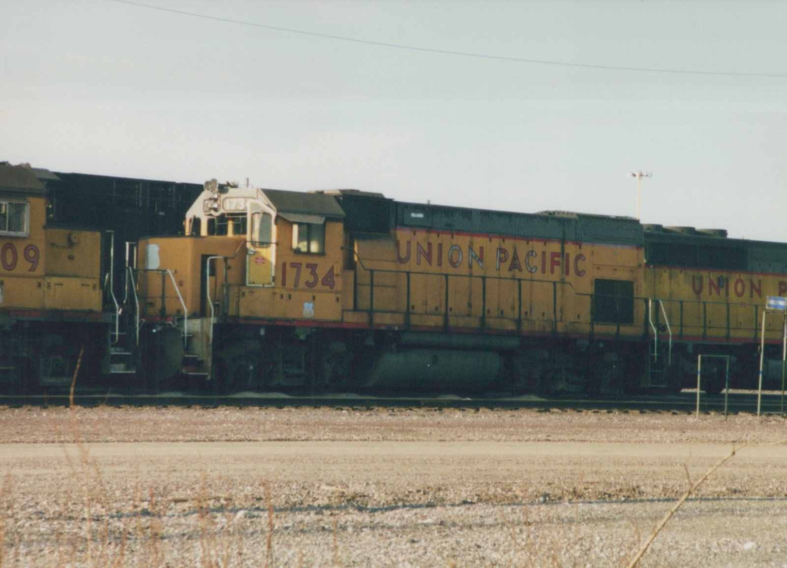 Side view of a yellow Union Pacific locomotive numbered 1734, with the number 09 on the unit behind it, on railroad tracks in a yard.