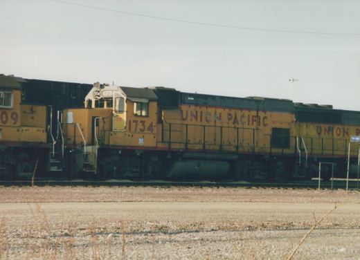 Side view of a yellow Union Pacific locomotive numbered 1734, with the number 09 on the unit behind it, on railroad tracks in a yard.