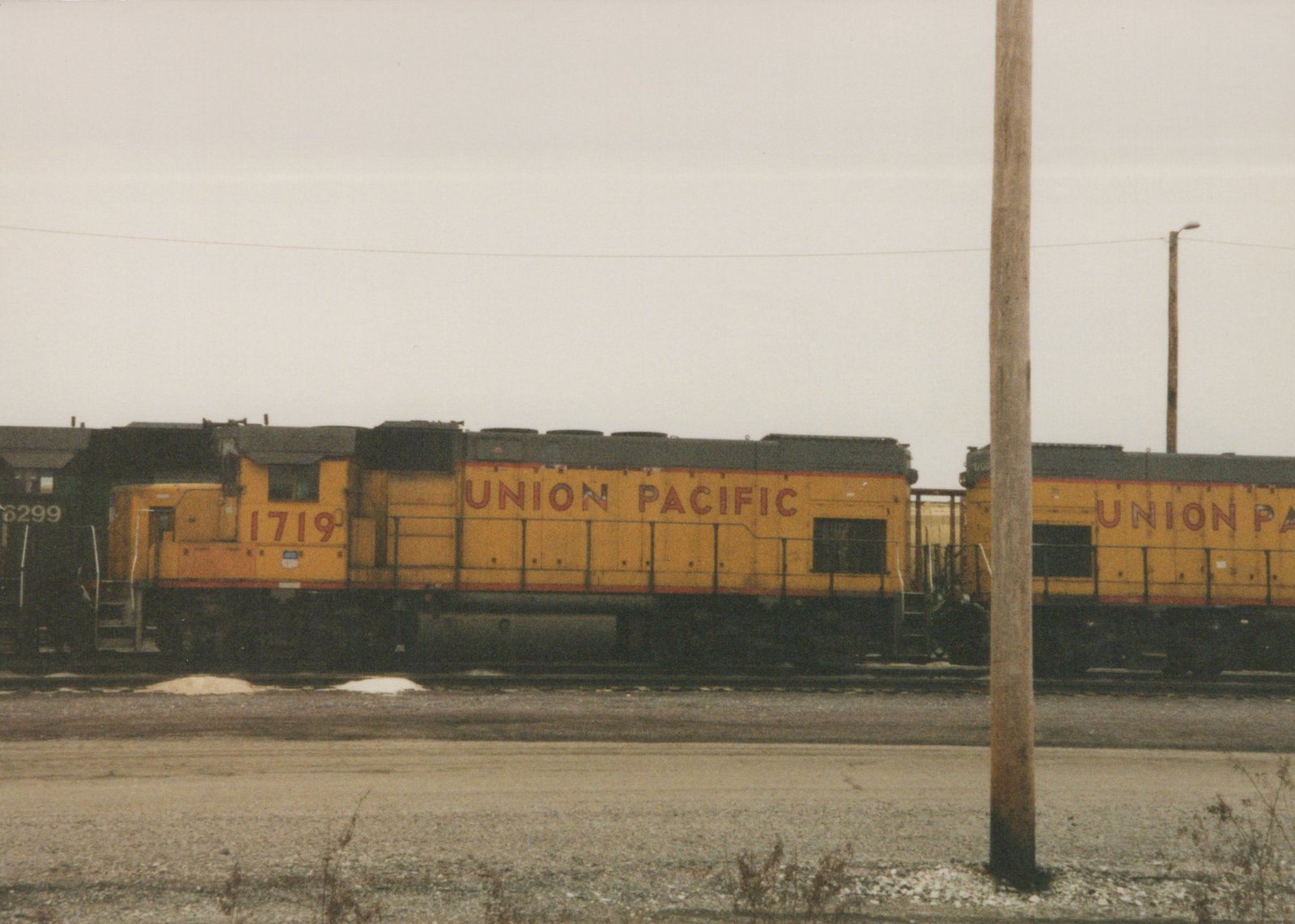 A yellow Union Pacific diesel locomotive, number 1719, is parked on a railroad track in a yard on a winter day.