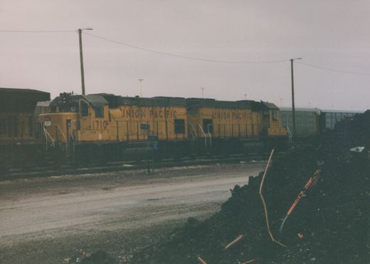 A side view of two yellow Union Pacific diesel locomotives, numbered 1710 and 1735, standing on tracks in a yard under a gray sky.