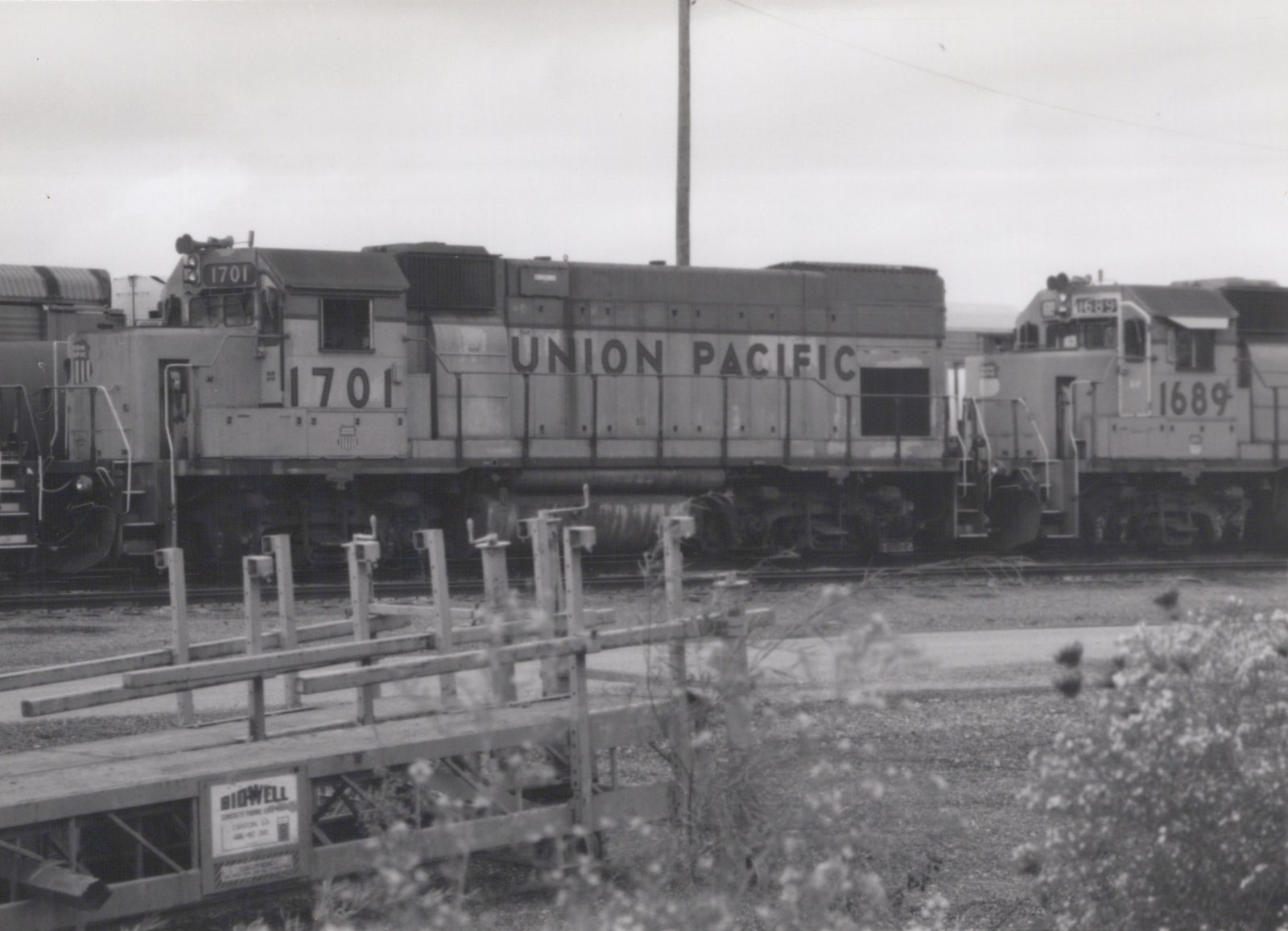 Black and white photo of two Union Pacific diesel locomotives, numbers 1701 and 1689, standing on parallel tracks in a yard with some wooden equipment in the foreground.