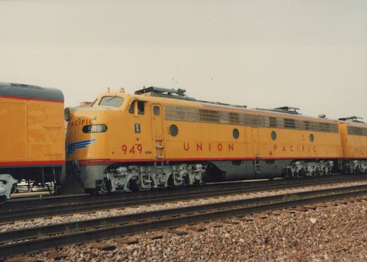 Two yellow Union Pacific E9 diesel locomotives, numbered 949 and 963, are parked on parallel tracks in a yard under an overcast sky.