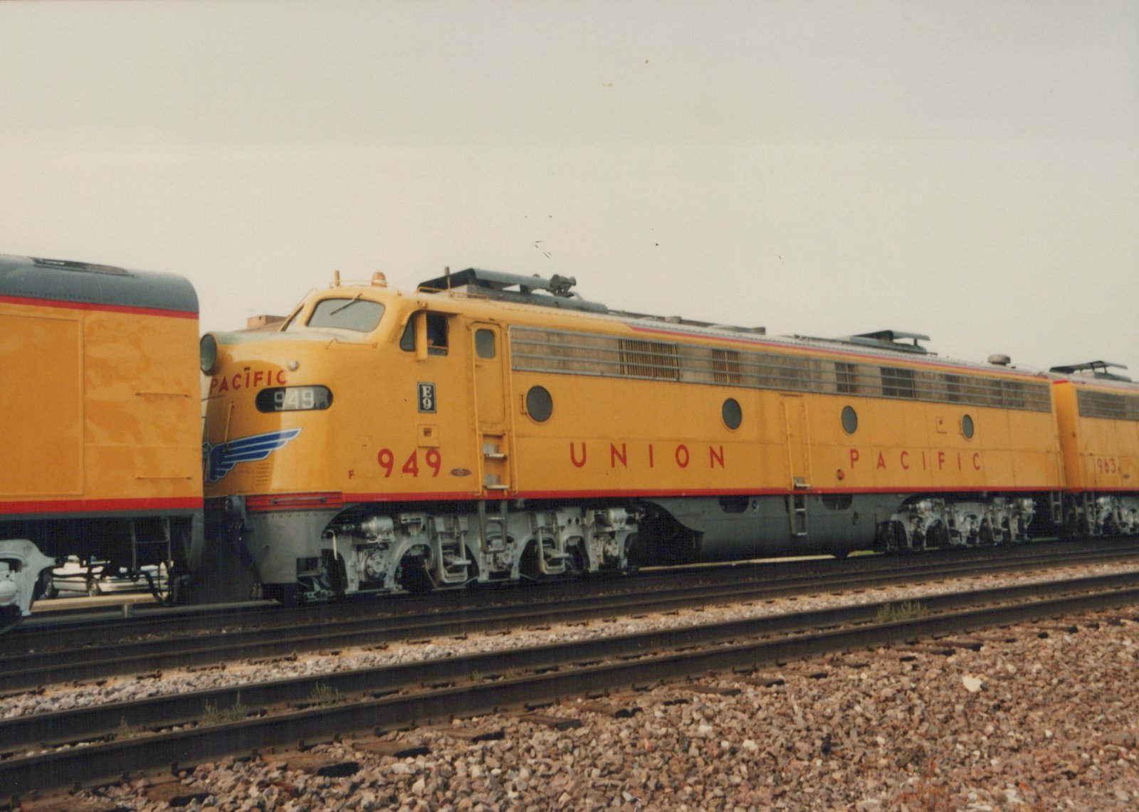 Two yellow Union Pacific E9 diesel locomotives, numbered 949 and 963, are parked on parallel tracks in a yard under an overcast sky.