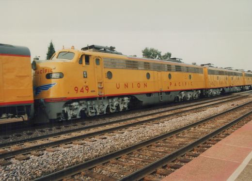 A yellow Union Pacific E9 diesel locomotive, number 949, is parked at a station platform, with a matching second unit, number 963, visible behind it.