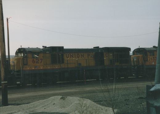 A side view of two Union Pacific diesel locomotives, numbers 627 and 2652, parked in a gravel rail yard under an overcast sky.