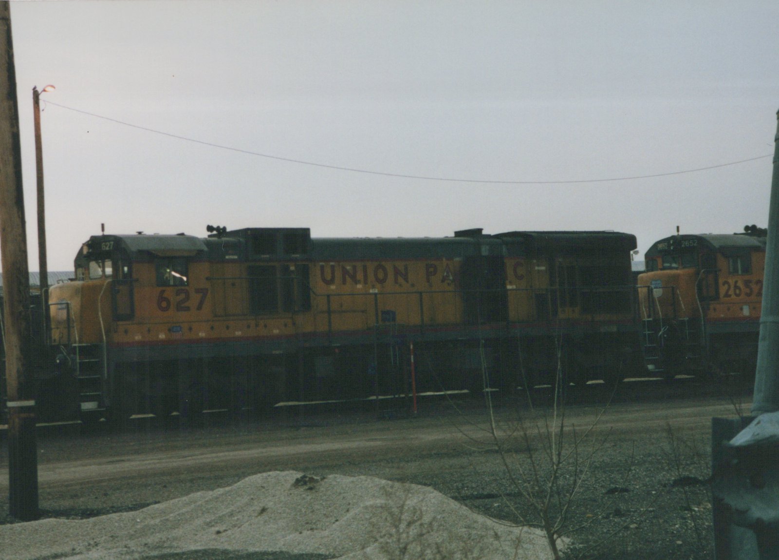A side view of two Union Pacific diesel locomotives, numbers 627 and 2652, parked in a gravel rail yard under an overcast sky.