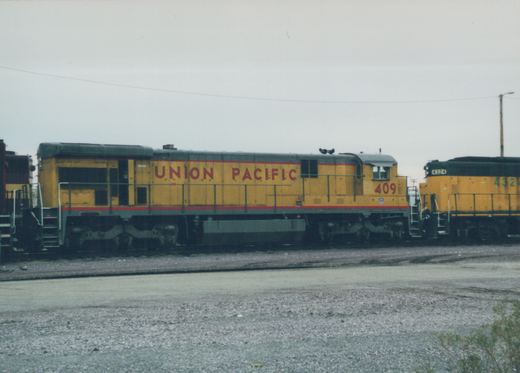 Two Union Pacific diesel locomotives, numbers 409 and 4324, are parked side by side in a gravel-covered rail yard under an overcast sky.