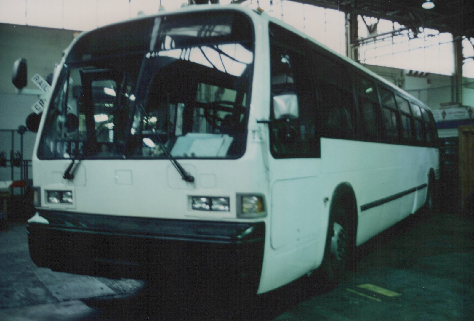 A front three-quarter view of a white Pace bus with the number 7 on its windshield, parked inside a large garage with high windows.