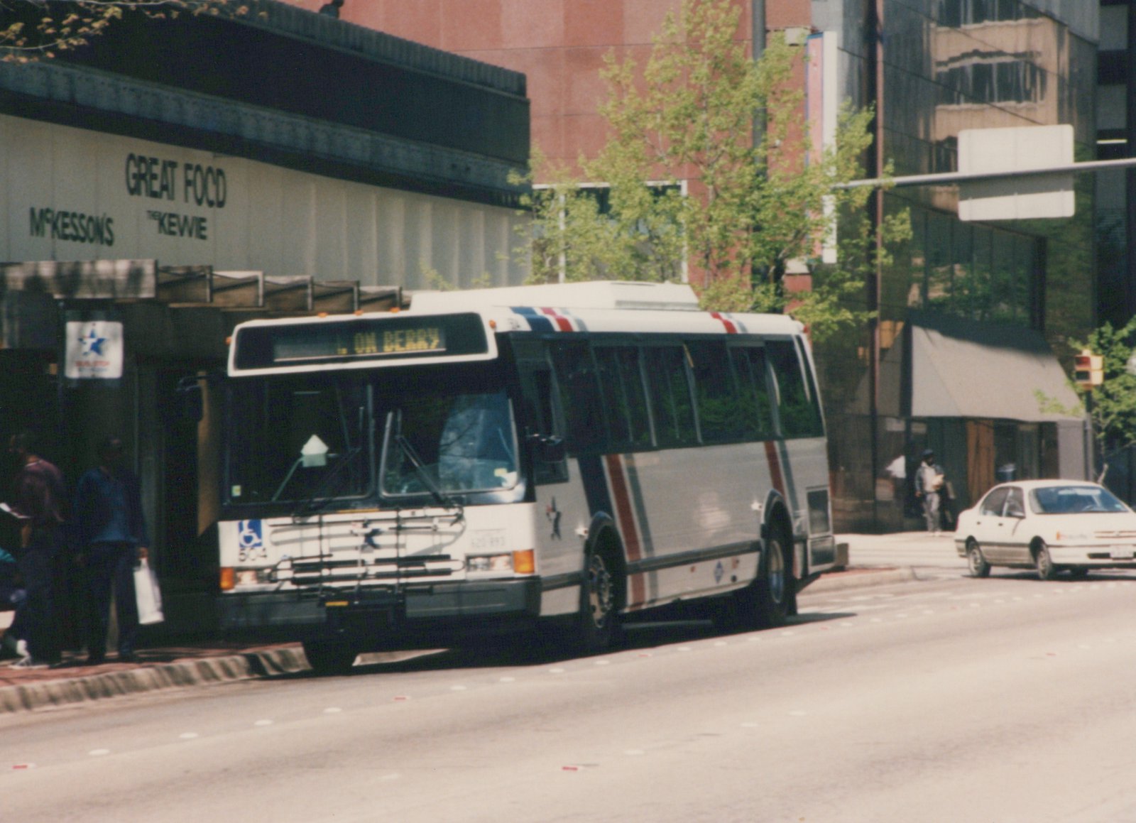A white Fort Worth Transit bus, number 504, is stopped on a city street with a destination sign reading 'L ON BERRY', with pedestrians nearby and storefronts in the background.