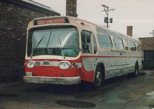 A red and cream CTA New Look bus, number 606, parked on a wet street with a brick building behind it, displaying route 353 Loop Express on its destination sign.