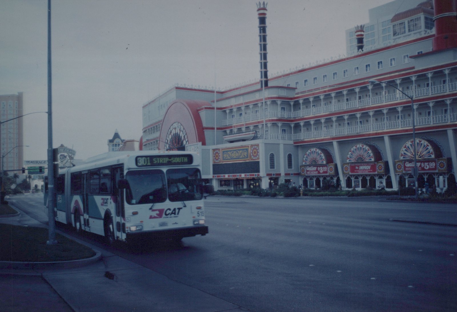 A white, teal, and magenta Clark County Area Transit bus with the number 515 and route 301 to Strip-South is shown on a city street, with a large, ornate building in the background.