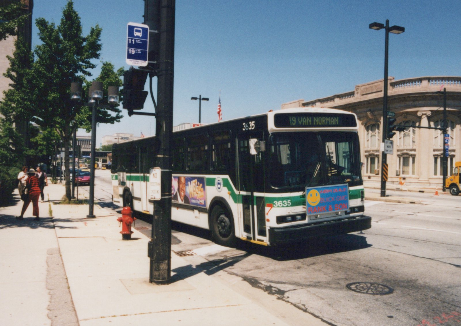 A white and green MCTS bus numbered 3635 with a '19 Van Norman' destination sign is stopped on a city street, with pedestrians and buildings in the background.