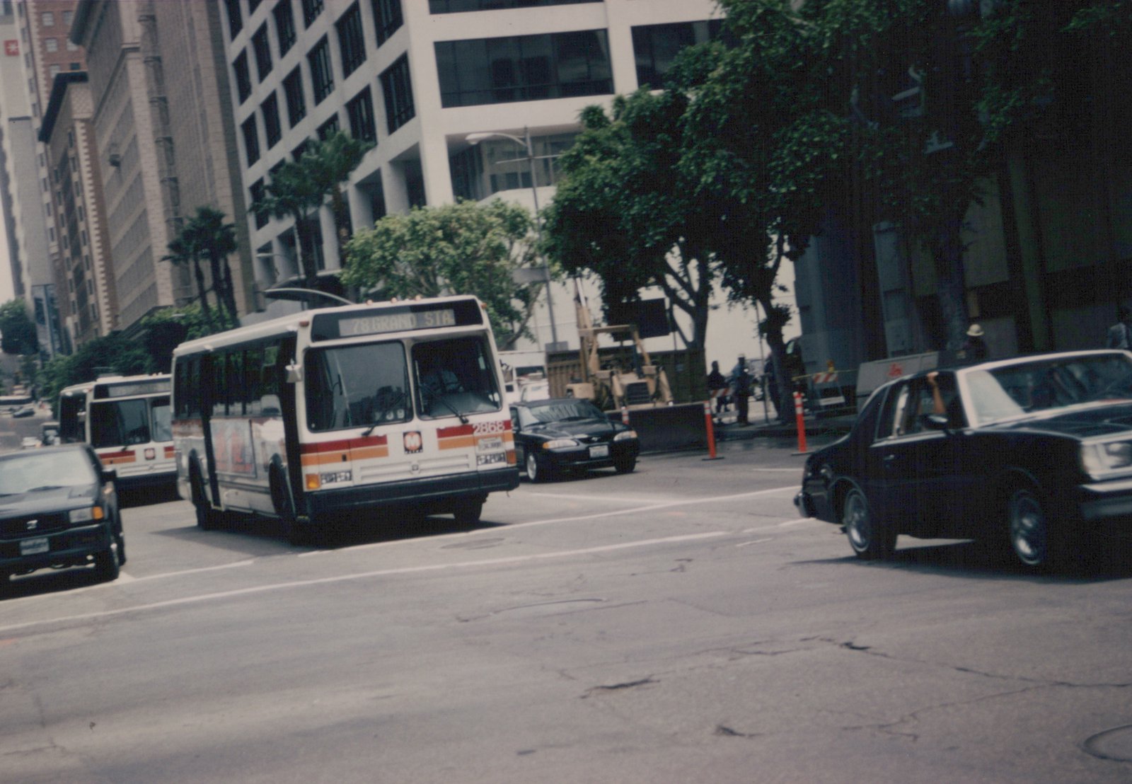 A white and orange Chicago Transit Authority bus with the number 2868 and destination '78 Grand Sta' is driving on a city street alongside cars and another bus.
