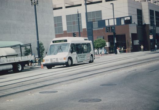 A white CTA bus labeled '31 EAST LOOP' is on a city street with tram tracks, modern buildings, and pedestrians on the sidewalk.
