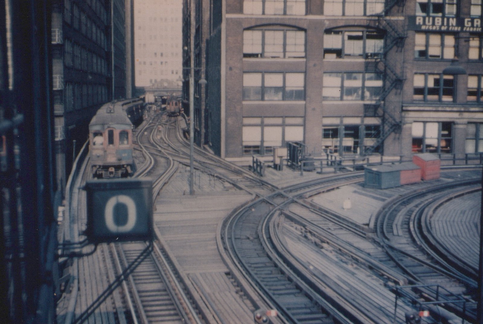 Two Chicago Aurora and Elgin interurban cars on an elevated track, surrounded by buildings.