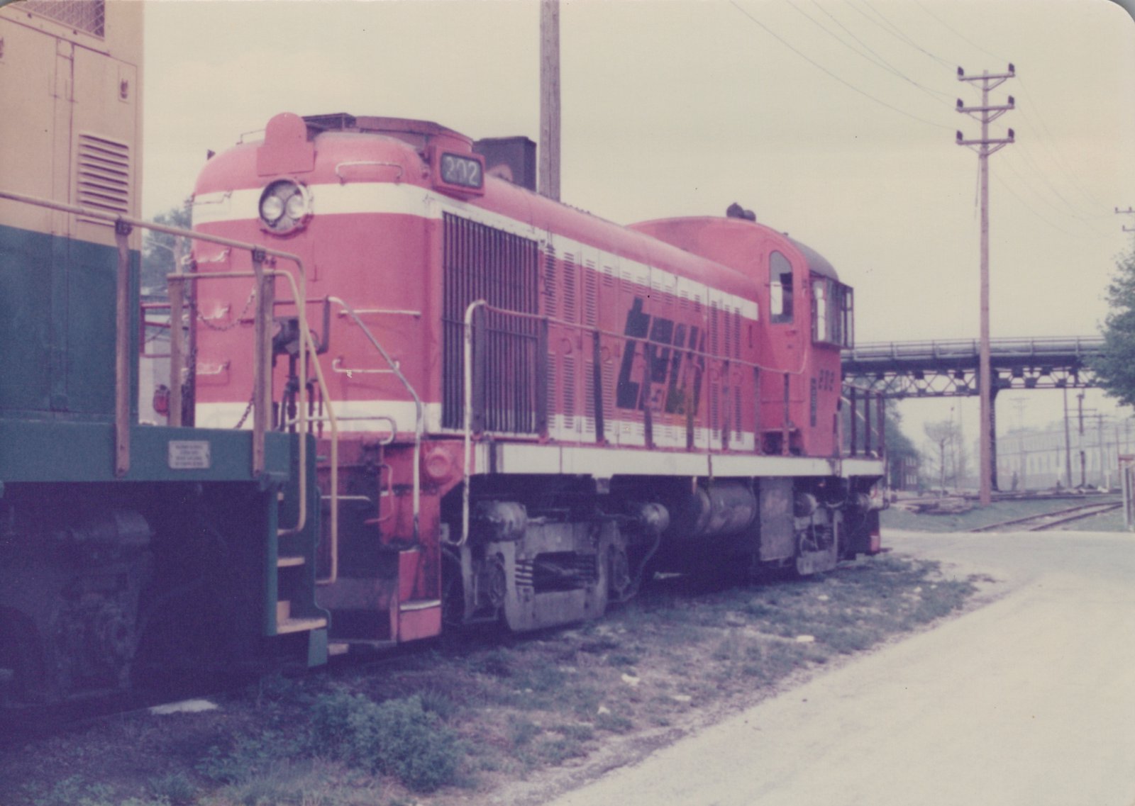 A red and white diesel locomotive with the number 202 and 'CHICAGO & NORTH WESTERN' lettering is shown in a three-quarter front view in a rail yard.