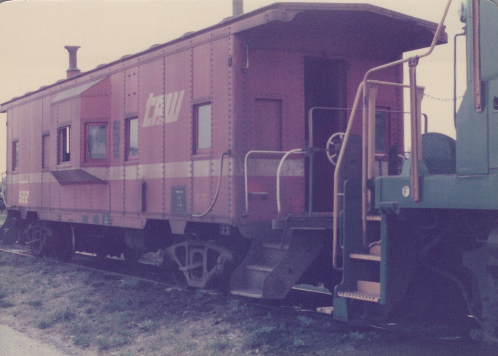A vintage maroon and white Chicago Great Western caboose, numbered 522, photographed from a three-quarter rear angle on a grassy trackside.
