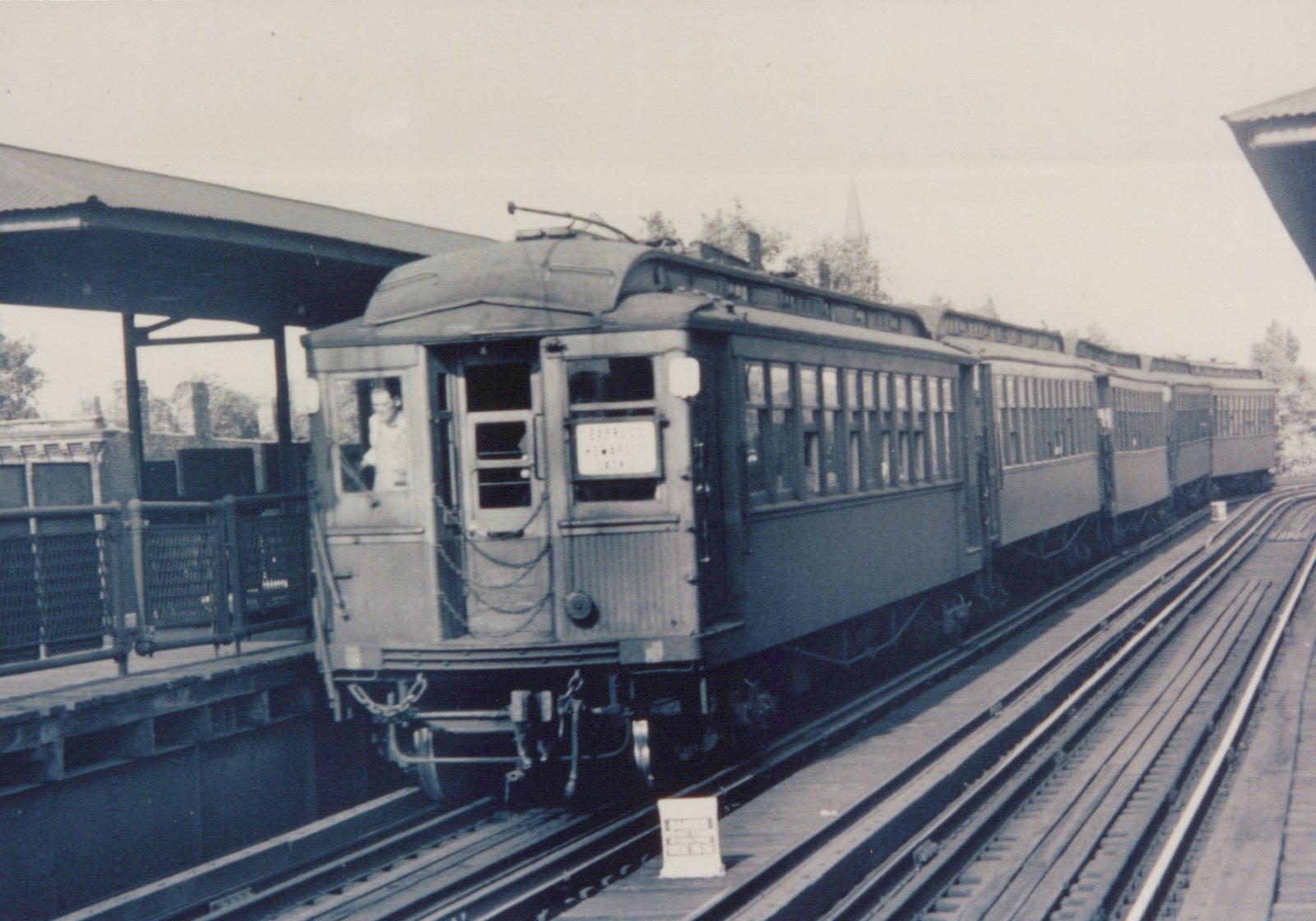 A black-and-white photo of a Chicago Rapid Transit Company rapid transit train at an elevated station, showing the front of the lead car with a destination sign and a person in the cab.