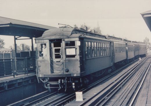 A black-and-white photo of a Chicago Rapid Transit Company rapid transit train at an elevated station, showing the front of the lead car with a destination sign and a person in the cab.