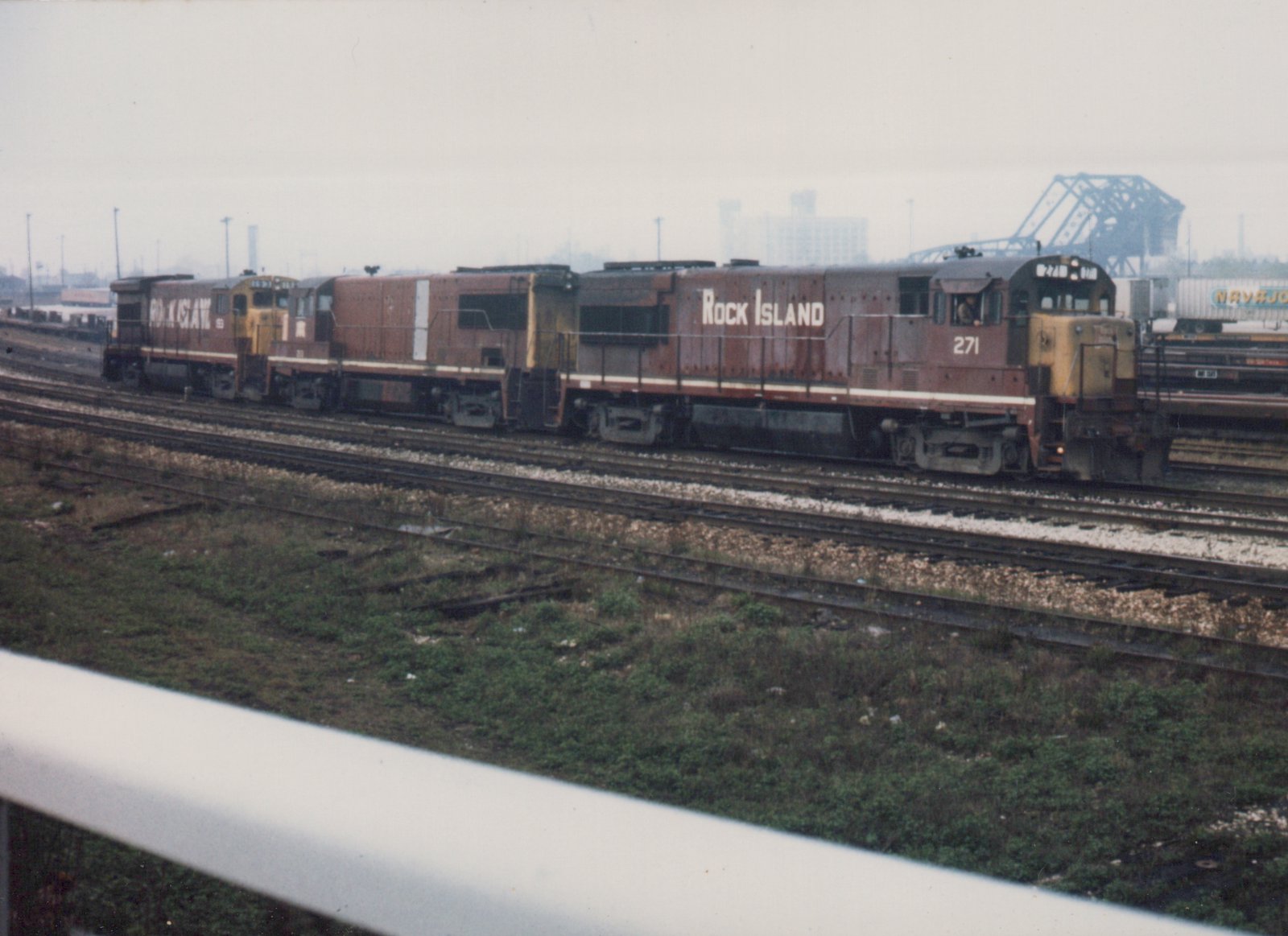 Two diesel locomotives in Rock Island livery, numbered 271 and 253, are pictured on multiple tracks in a rail yard with a hazy background.