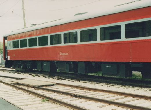 A red and white interurban railcar with the number 25 and the name Ravenswood on its side, sitting on tracks in a yard.