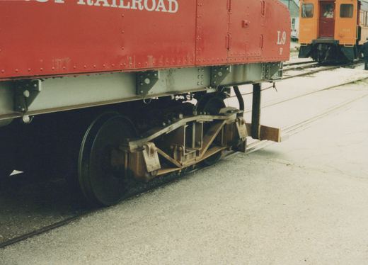 A close-up side view of a red interurban railcar, number L9, with an orange car numbered 1111 visible behind it on adjacent tracks.