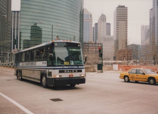 A white and blue charter bus with the number 91 on the front, labeled 'Dale's Charter Service,' is driving on a city street with tall glass buildings behind it and a yellow taxi nearby.