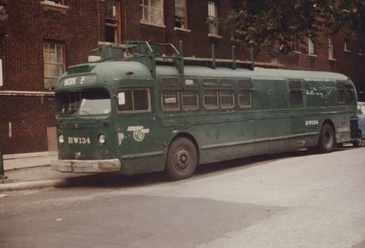 A dark green CTA bus, number BW134, parked on a street in front of a brick building, viewed from a three-quarter front angle.