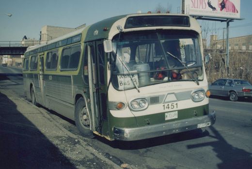 A green and cream CTA motor bus, number 1451, is parked on a city street in winter, with a handwritten 'Work Bus 3' sign on its windshield and a silver car in the background.