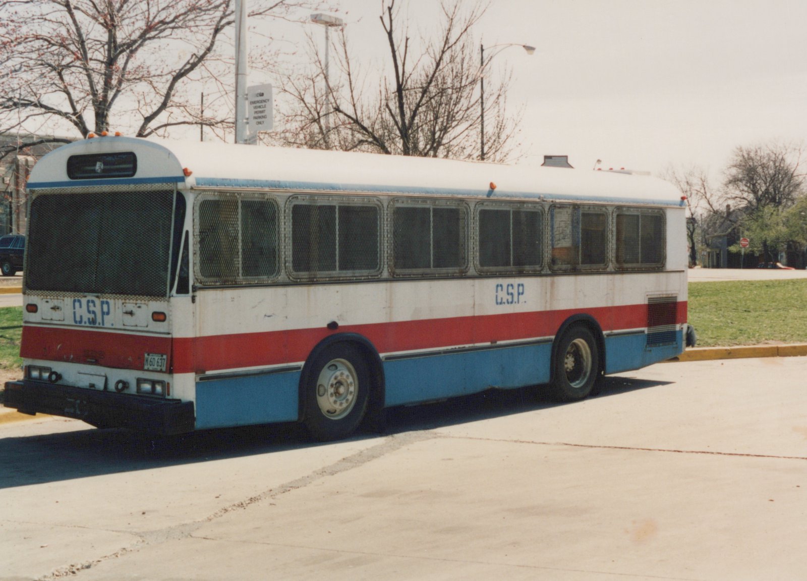 A three-quarter rear view of a white, red, and blue C.S.P. bus with a Flxible Metro body, parked on a paved street with bare trees and a CTA sign in the background.