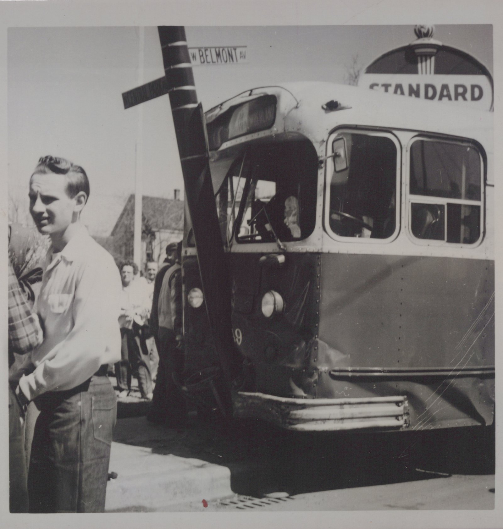 A black and white photo of a standard bus with number 49 at a street corner, with several people on the sidewalk.