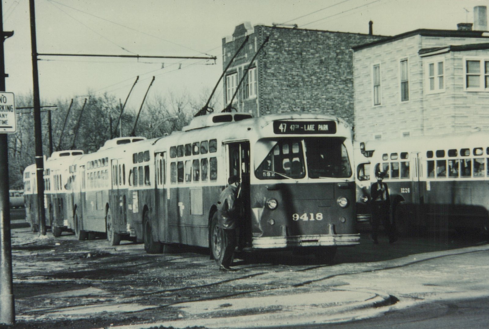 A black and white photo shows a CTA trolleybus with the number 9418 and route 47 to Lake Park, stopped on a street with a trolley pole raised, with another CTA bus nearby and a person boarding.