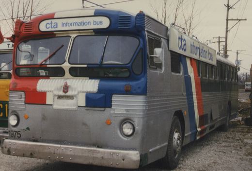 A silver CTA bus with red, white, and blue stripes, labeled 'Information bus', parked on a gravel lot under an overcast sky.