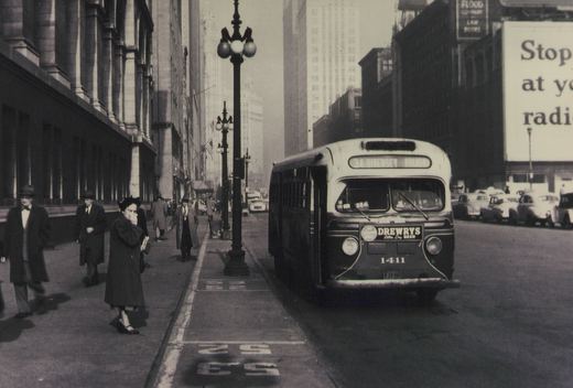 A vintage motor bus from the 1940s, marked with route 34 Diversey and fleet number 1411, is stopped on a busy Chicago street with pedestrians and period cars nearby.
