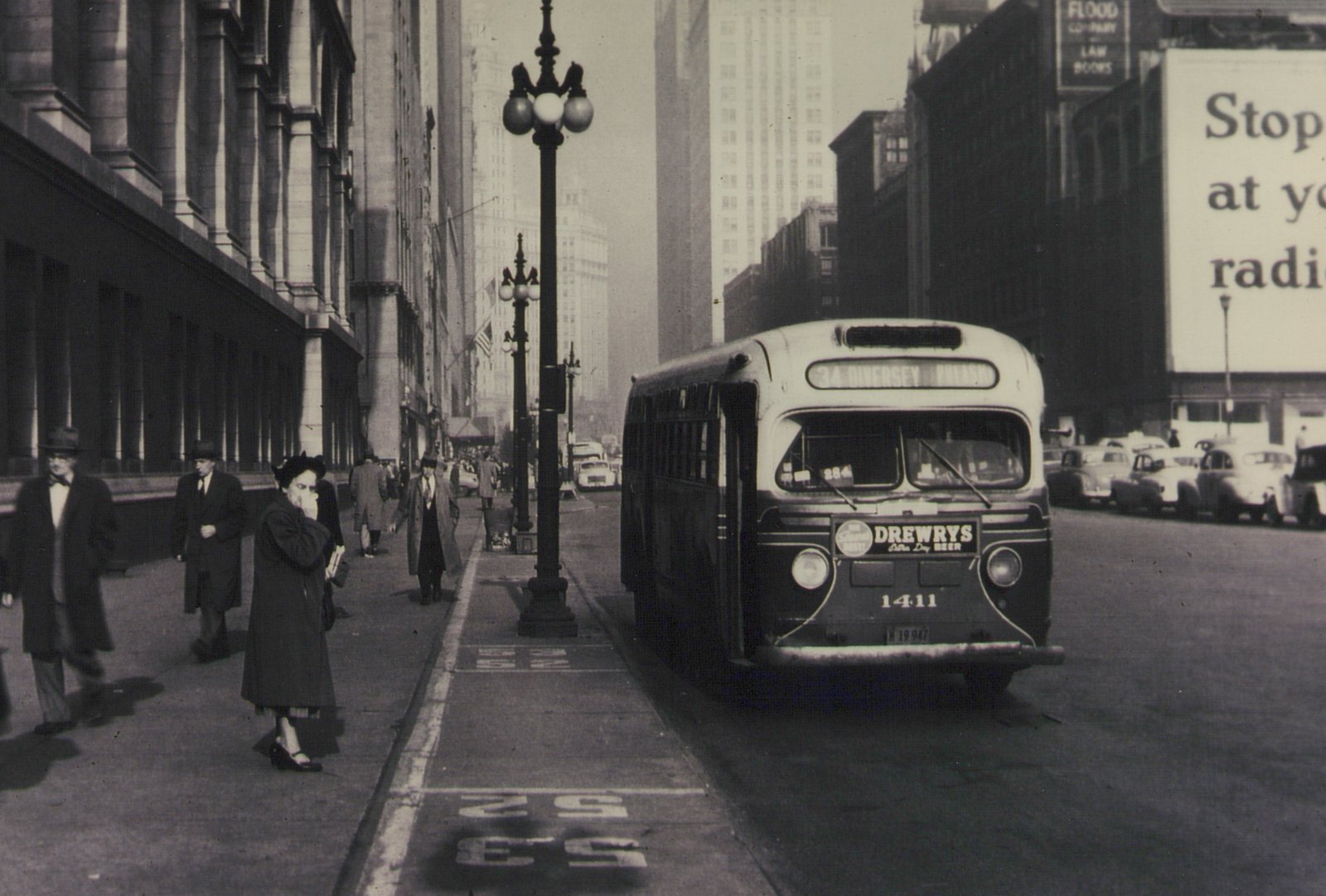 A vintage motor bus from the 1940s, marked with route 34 Diversey and fleet number 1411, is stopped on a busy Chicago street with pedestrians and period cars nearby.