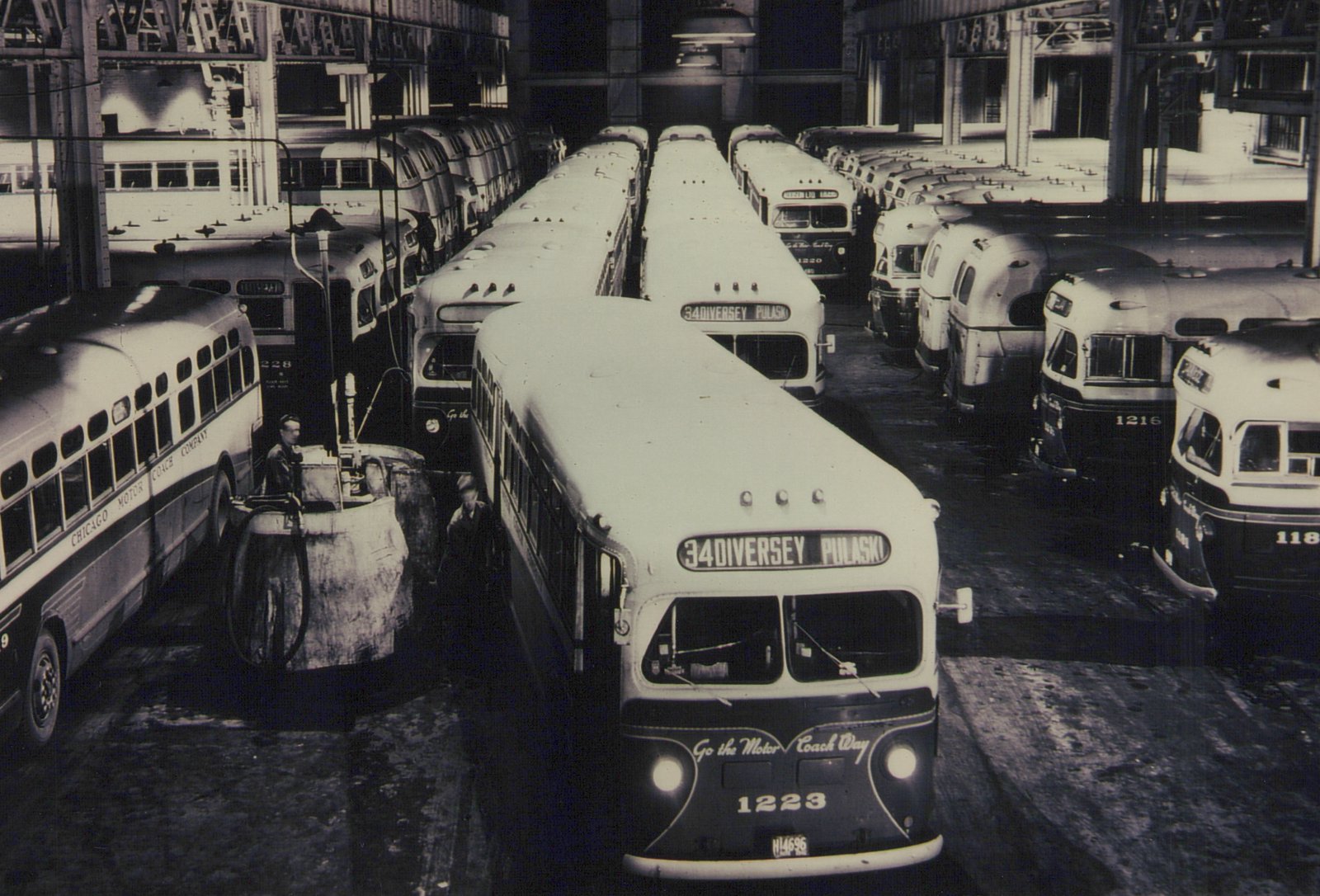 A black and white photo of a Chicago Motor Coach Company bus garage filled with numerous buses, with one bus in the foreground showing the destination sign '34 DIVERSEY PULASKI'.